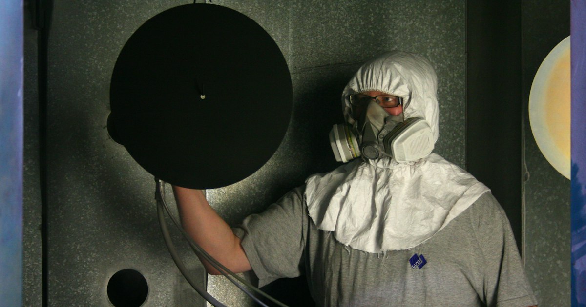 Industrial painter wearing a respirator inside a spray booth