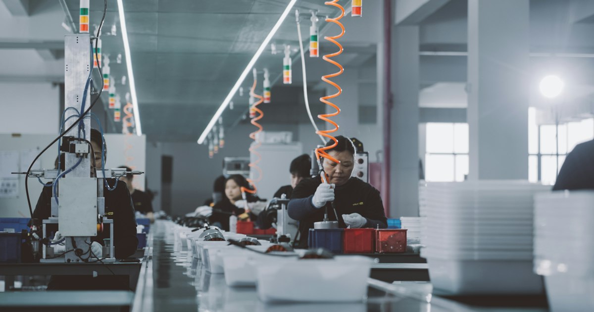 Technicians assembling products at workstations on an assembly line
