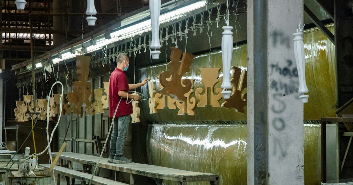 Operator spray coating metal parts hanging from an overhead conveyor line